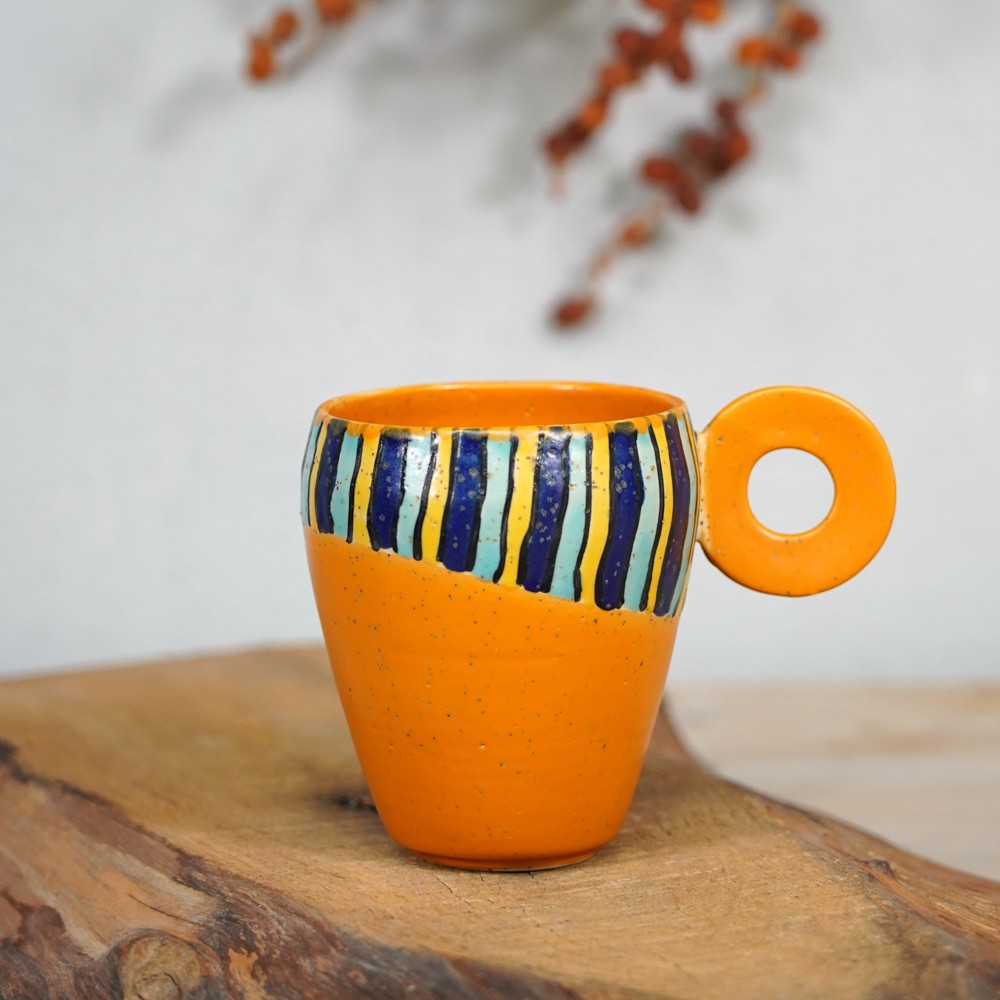 ceramic mug with vertical colorful stripes and orange background