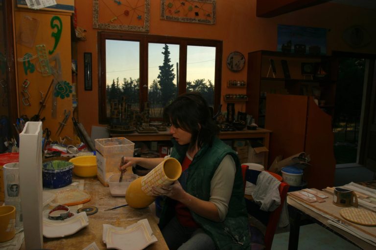 Ceramist Stella Nedoglou painting a handmade ceramic vase in her pottery studio near Thessaloniki, Greece