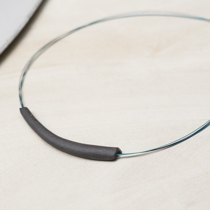 Curved matte black ceramic wire necklace with elongated handmade ceramic element