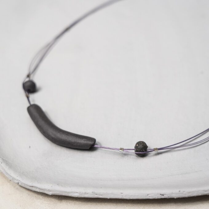 curved matte black ceramic necklace with textured bead