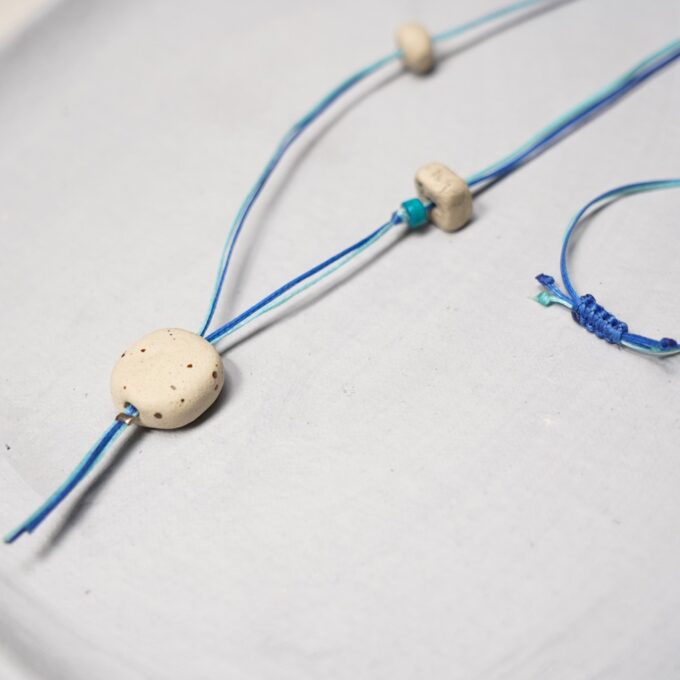 speckled off-white ceramic bead necklace with blue waxthread