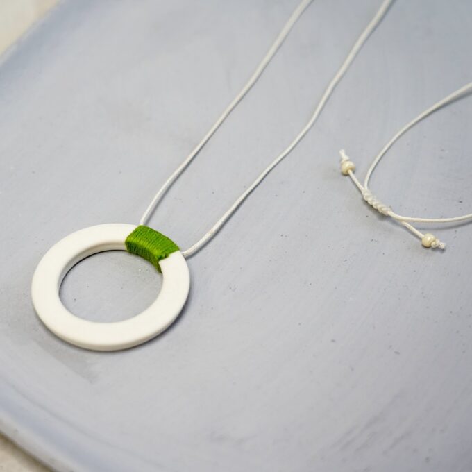 off-white ceramic ring necklace with green thread wrap and waxthread