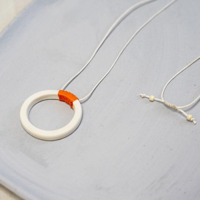 off-white ceramic ring necklace with orange thread wrap and waxthread