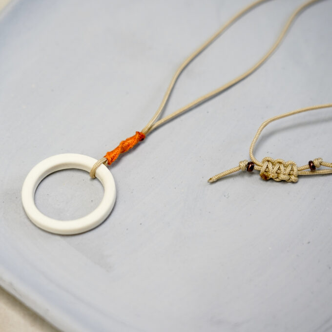 off-white ceramic ring necklace with orange thread wrap and waxthread