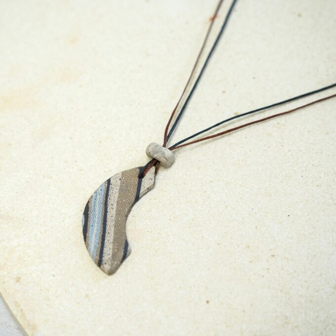 asymmetrical striped ceramic curve necklace with waxthread on neutral background