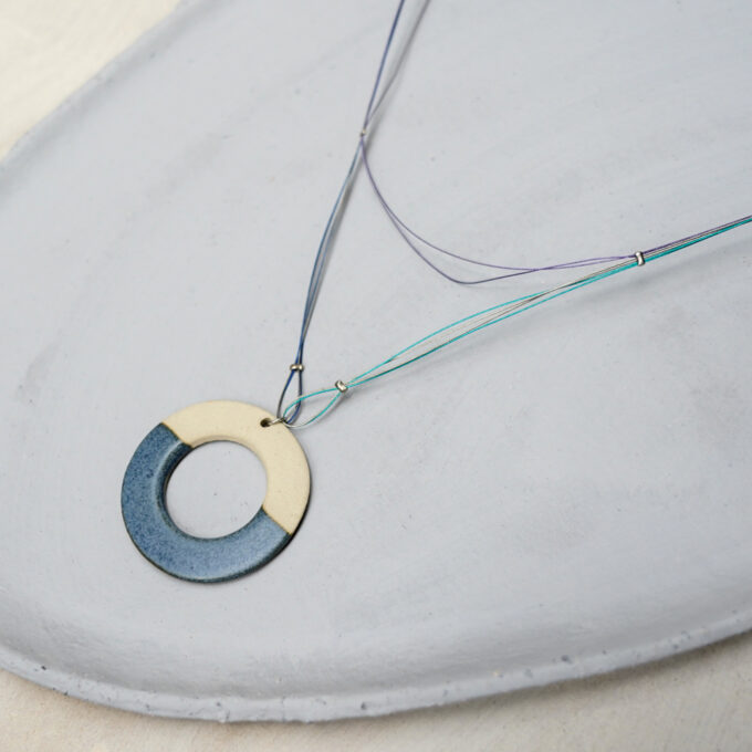 two tone circular ceramic wire necklace on neutral surface